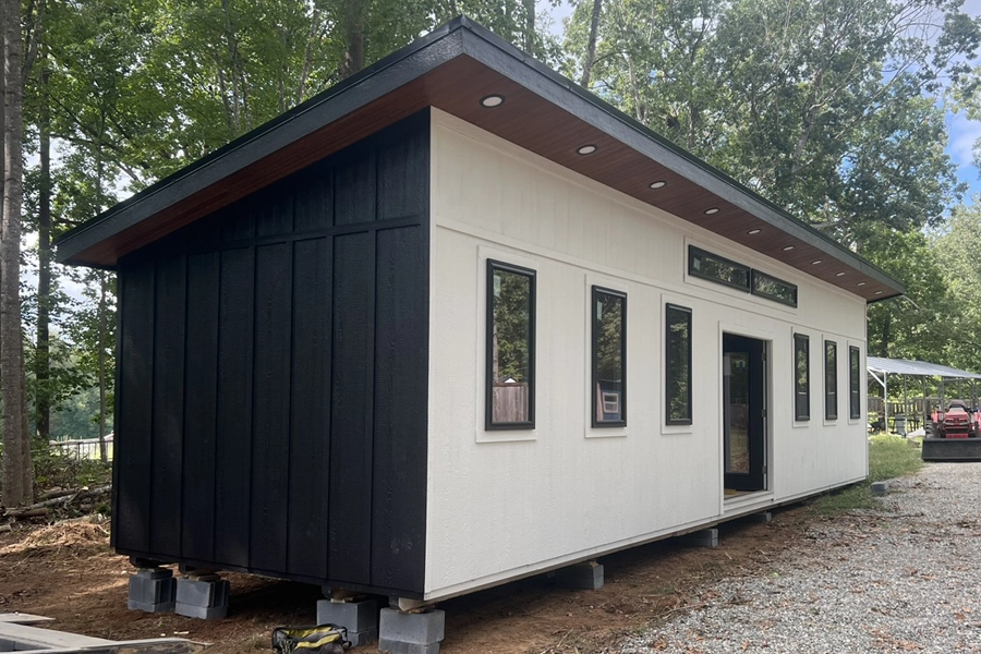 A tiny house is being built in a wooded area.